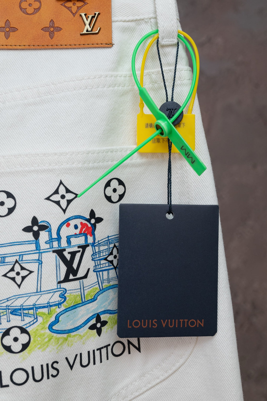 White denim pants with LV emblem print and hanging Louis Vuitton tag
