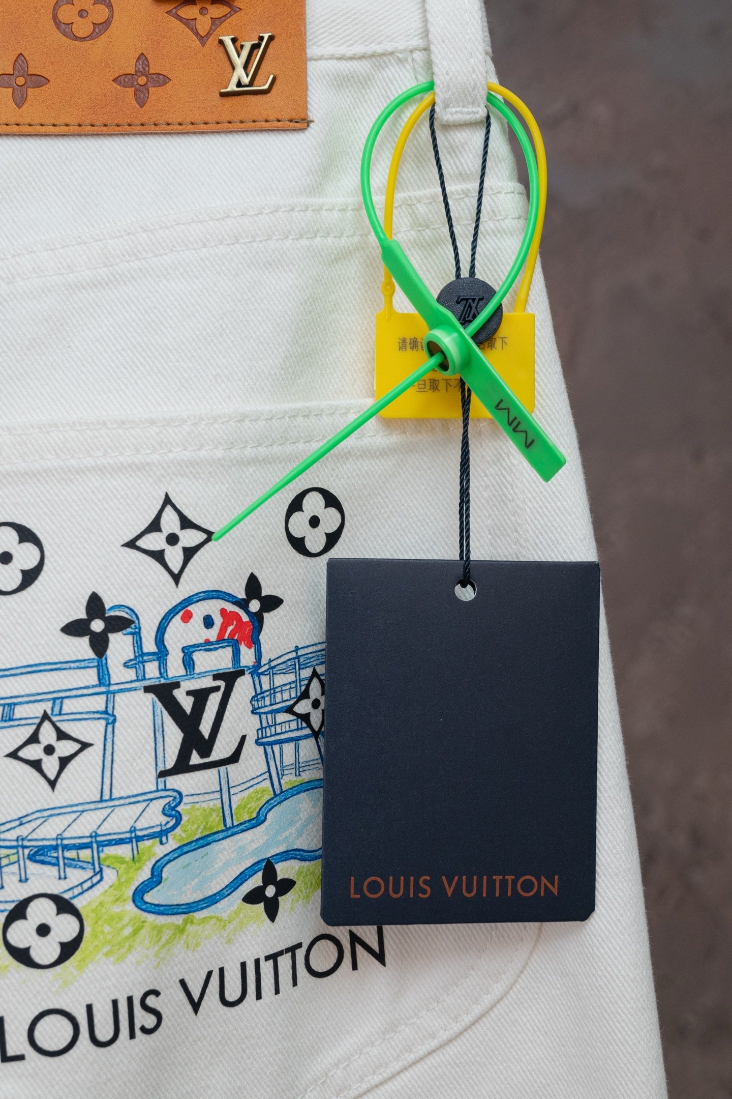 White denim pants with LV emblem print and hanging Louis Vuitton tag