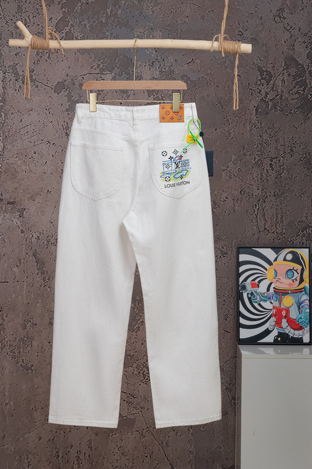 White denim pants with button fly and logo patch at right hip