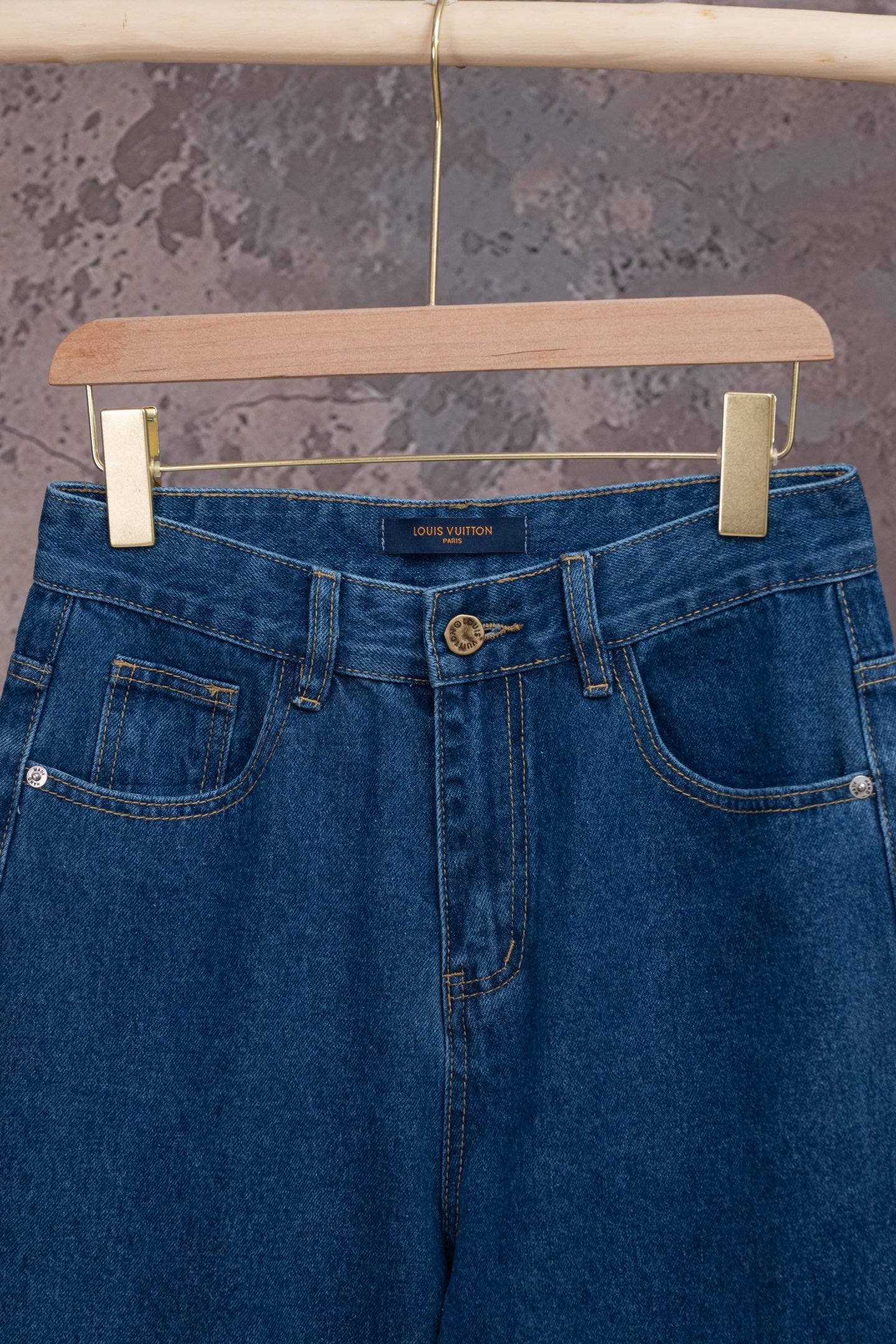 Blue denim jeans with logo patch, belt loops, and button closure