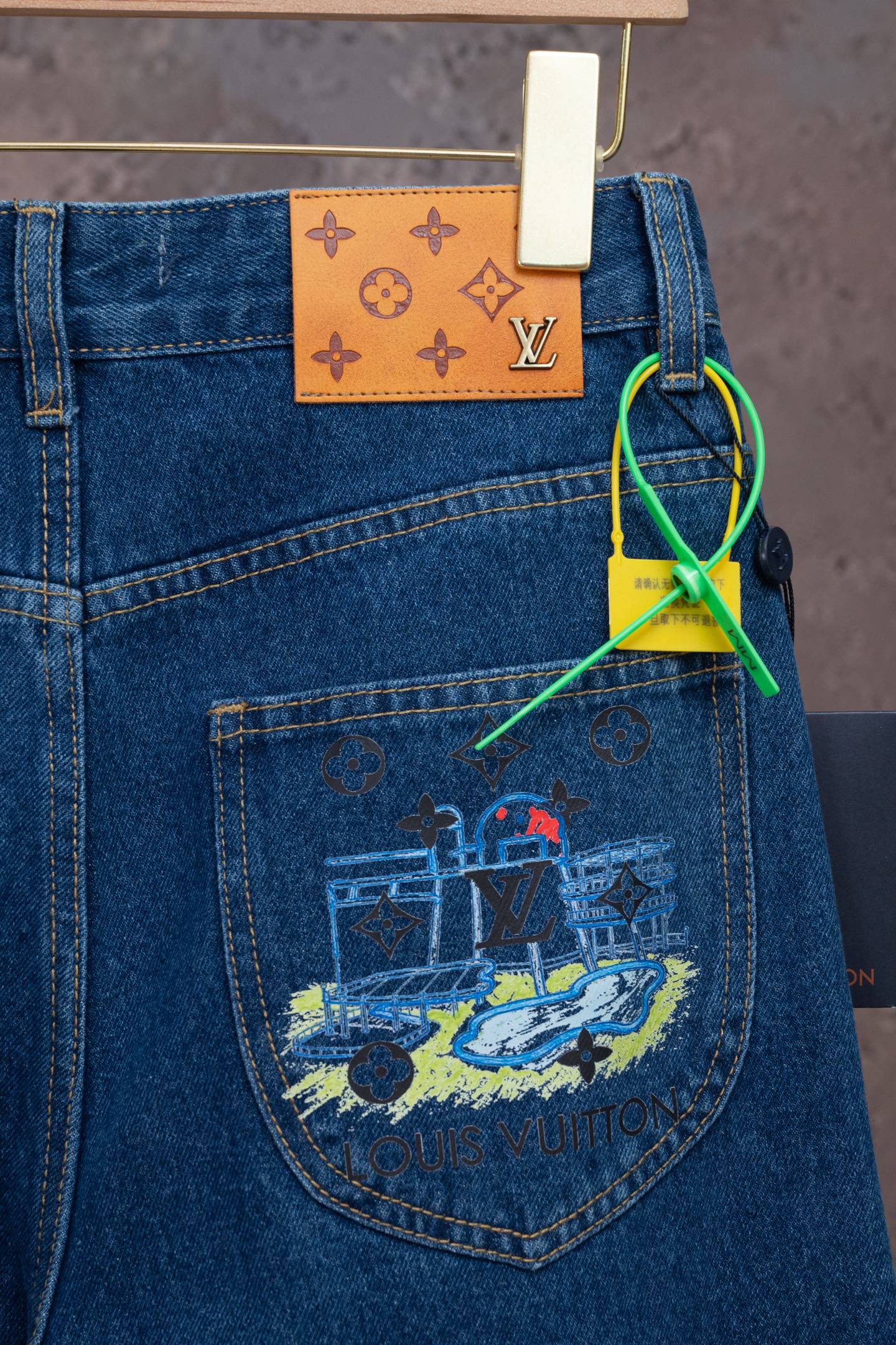 Blue denim jeans with colorful back-pocket graphic and hanging tag