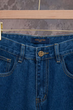 Blue denim jeans waistband close-up with logo patch and zipper fly