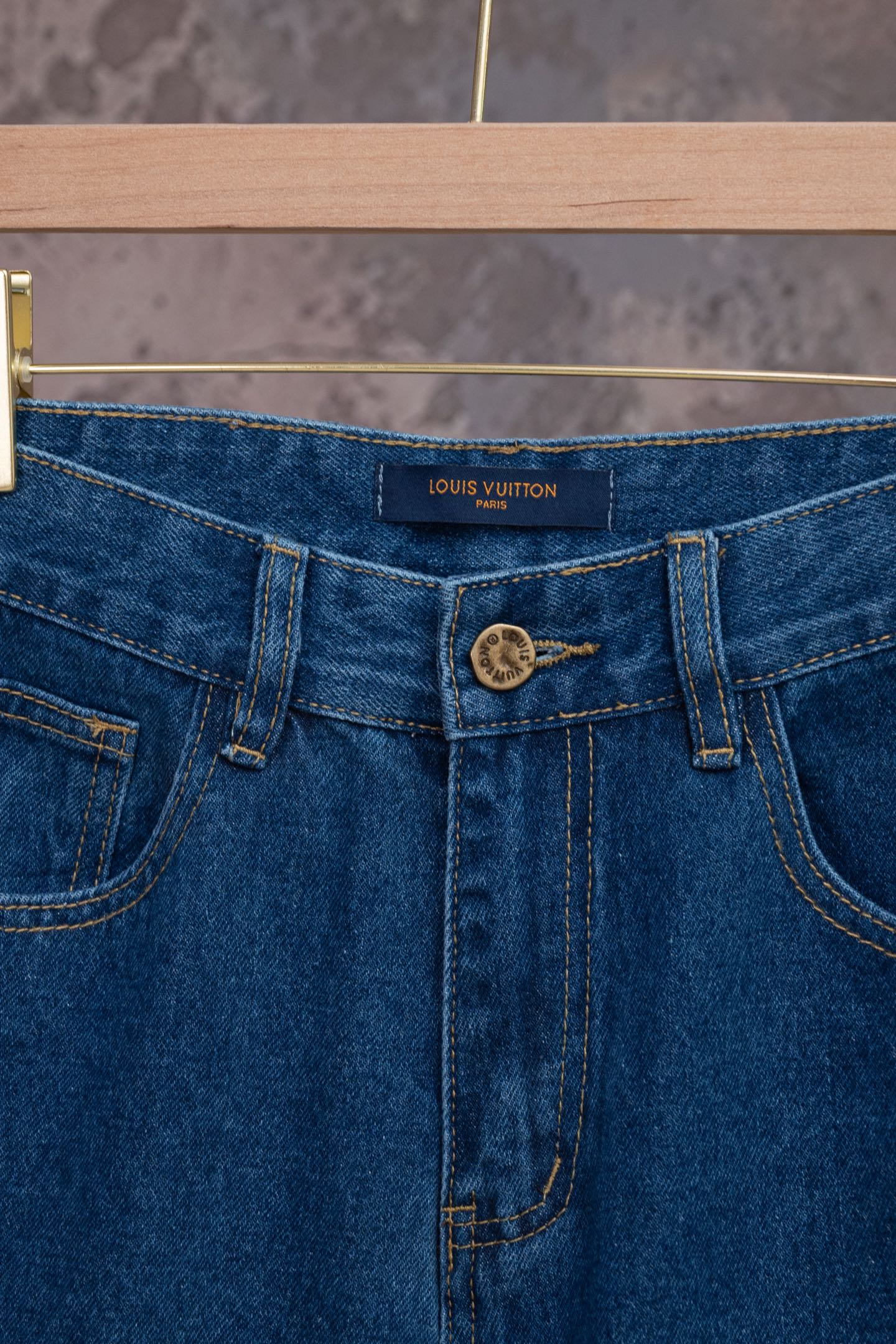 Blue denim jeans waistband close-up with logo patch and zipper fly