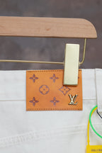 White Louis Vuitton pants close-up with leather-look logo patch at waistband