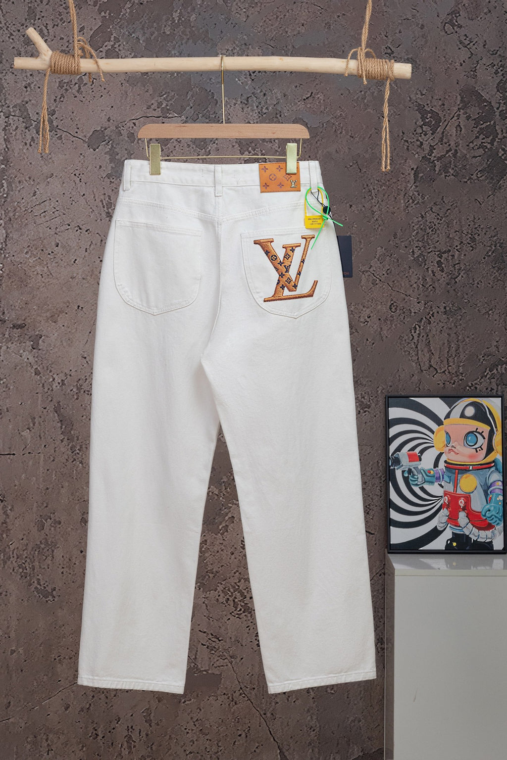 White Louis Vuitton pants on hanger with LV graphic patch on right pocket
