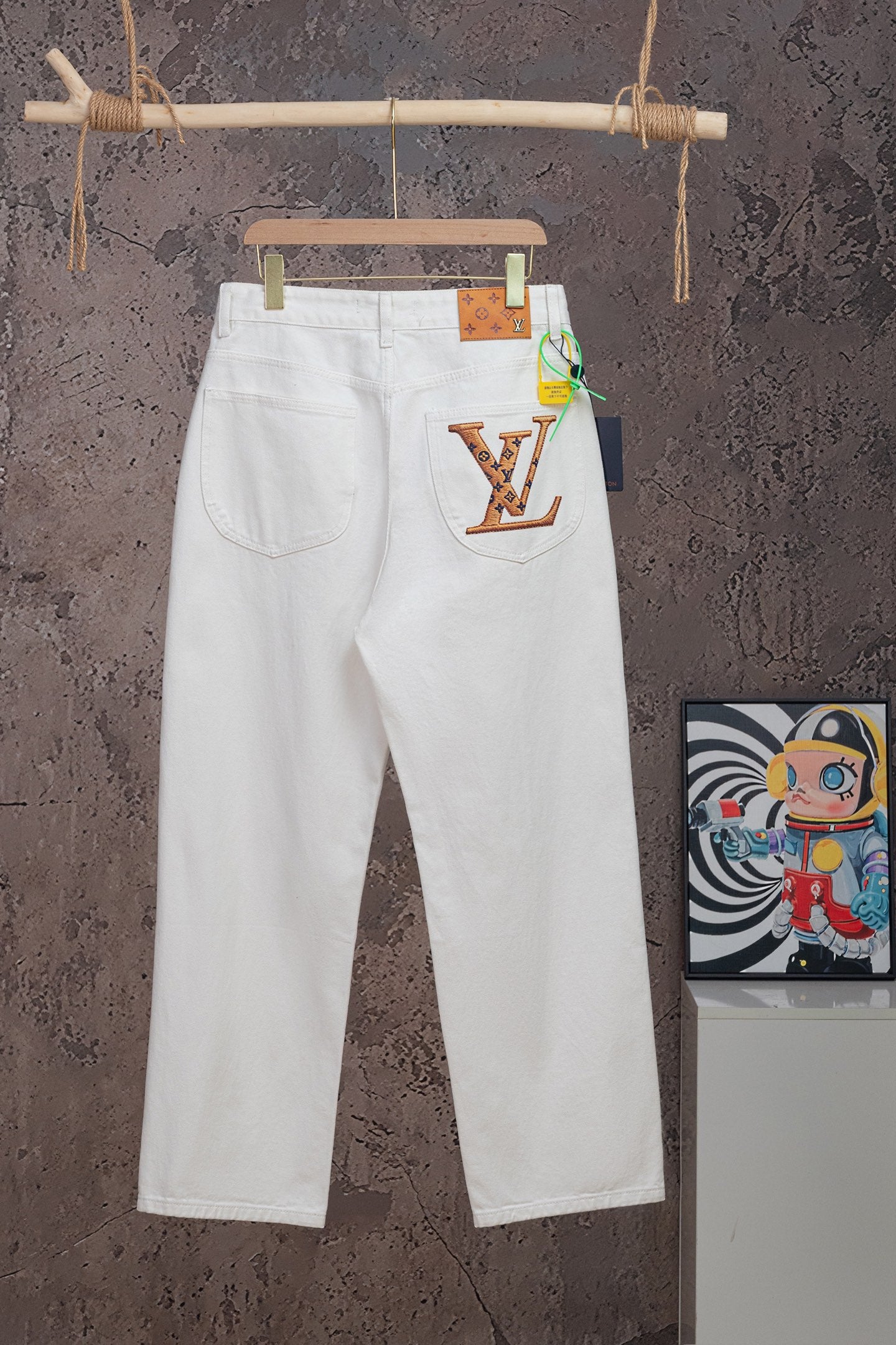 White Louis Vuitton pants on hanger with LV graphic patch on right pocket