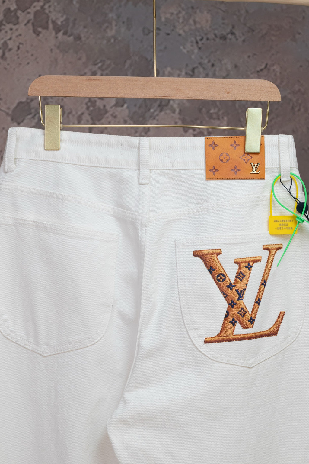 White Louis Vuitton pants with LV logo patch on front pocket and waistband tag