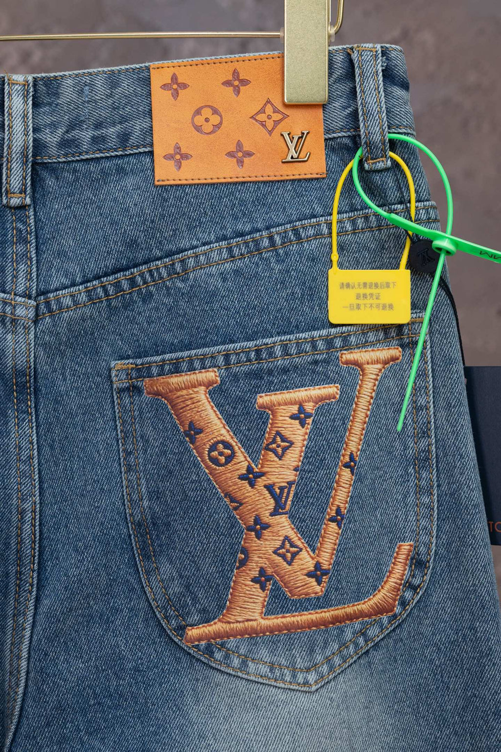 Light blue denim pocket with large tan LV monogram design and orange patch