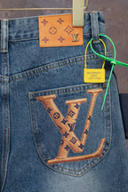 Light blue denim pocket with large tan LV monogram design and orange patch