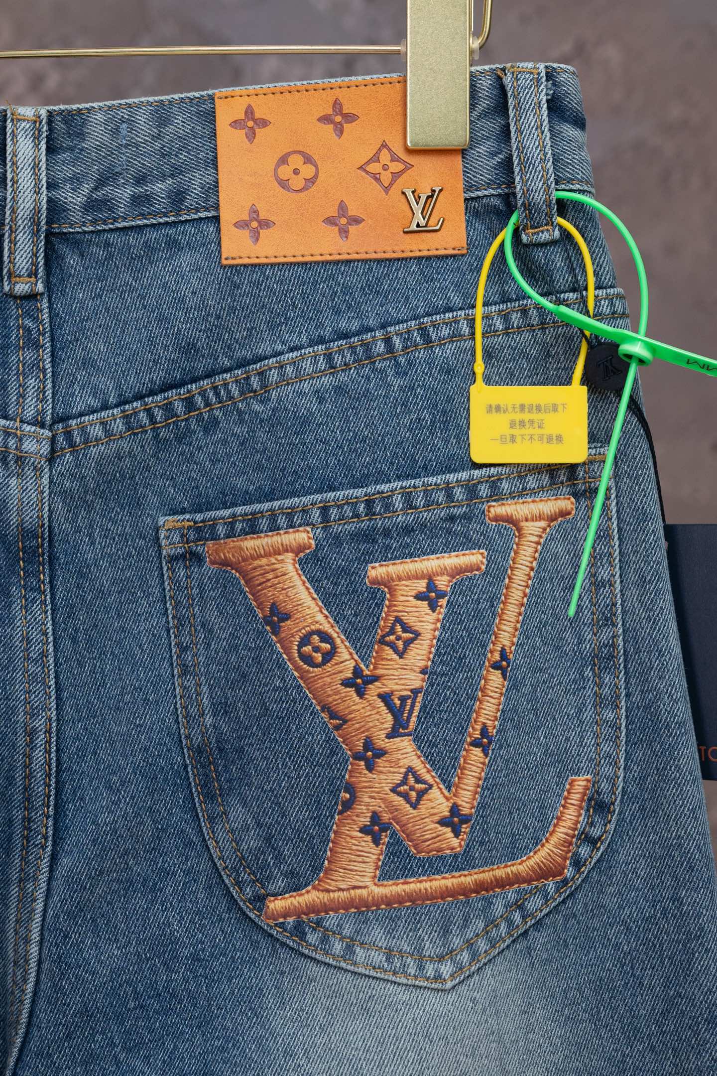 Light blue denim pocket with large tan LV monogram design and orange patch