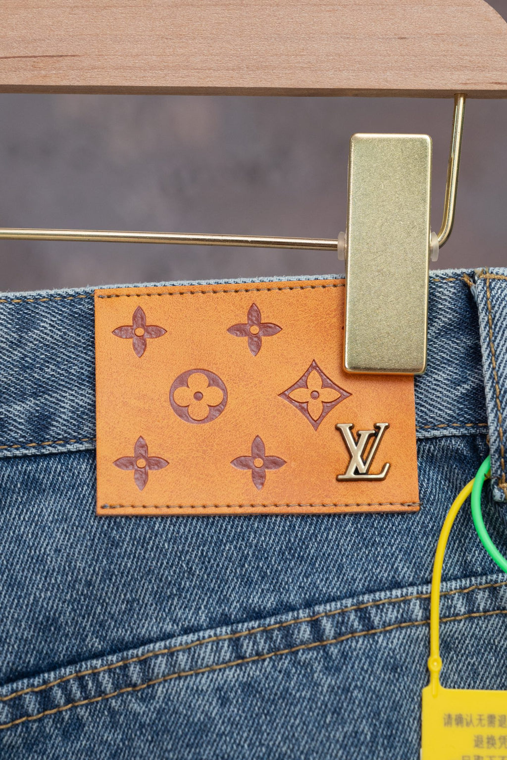 Leather LV monogram patch on light blue denim pocket, orange background