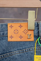 Leather LV monogram patch on light blue denim pocket, orange background