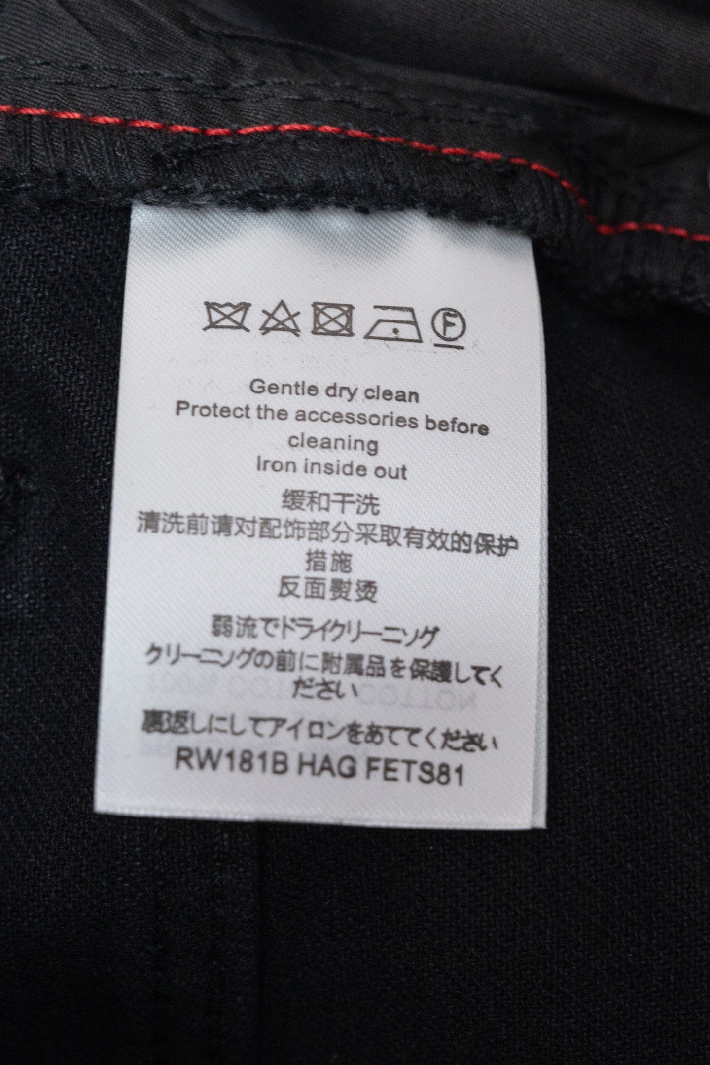 Care label on black denim pants with washing instructions
