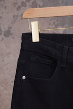 Black denim pants with back waistband and stitched back pocket, close-up