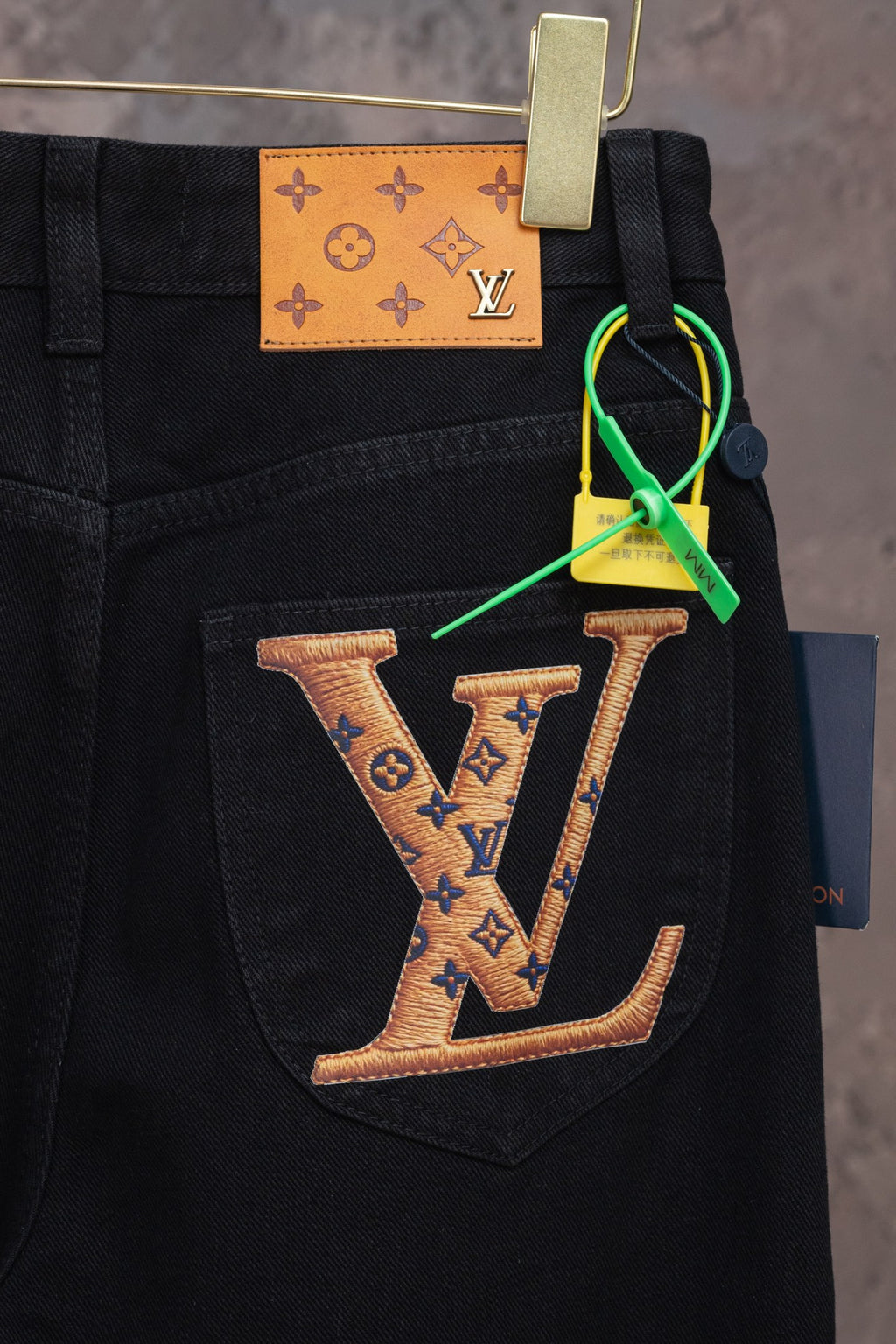 Black denim pants with front pocket and belt loops, with LV keychain tag