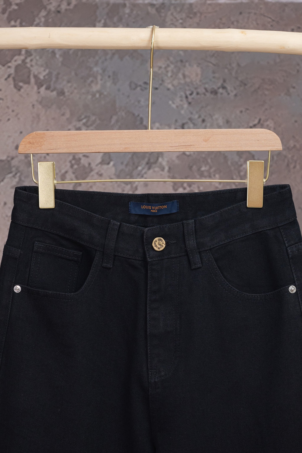 Black denim pants with front pockets and center button, close-up view