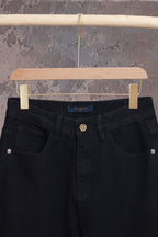 Black denim pants with front pockets and center button, close-up view