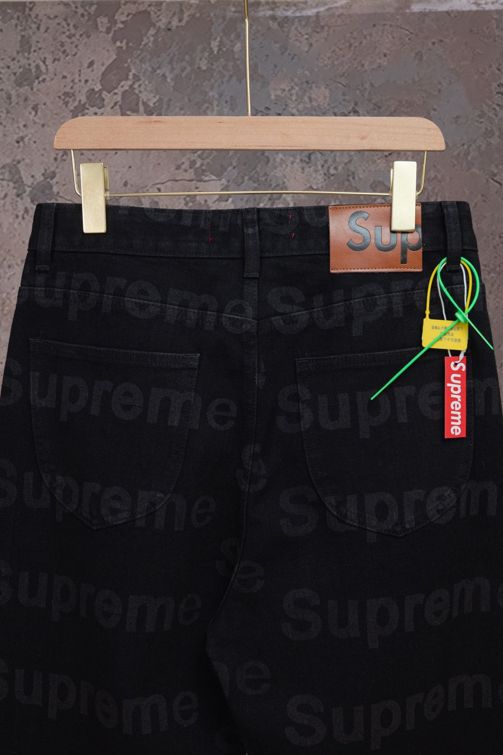 Black denim pants side view with pocket and hanging Supreme tag