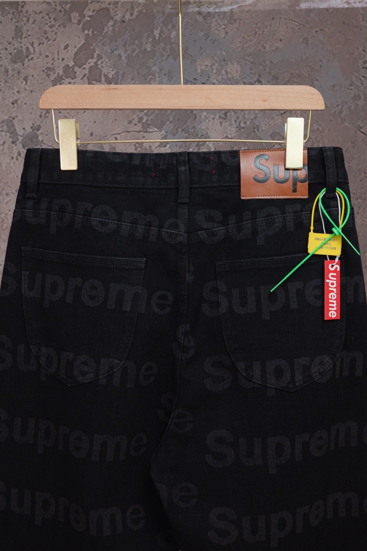 Black denim pants side view with pocket and hanging Supreme tag