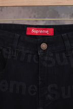 Black denim pants waistband close-up with red Supreme label