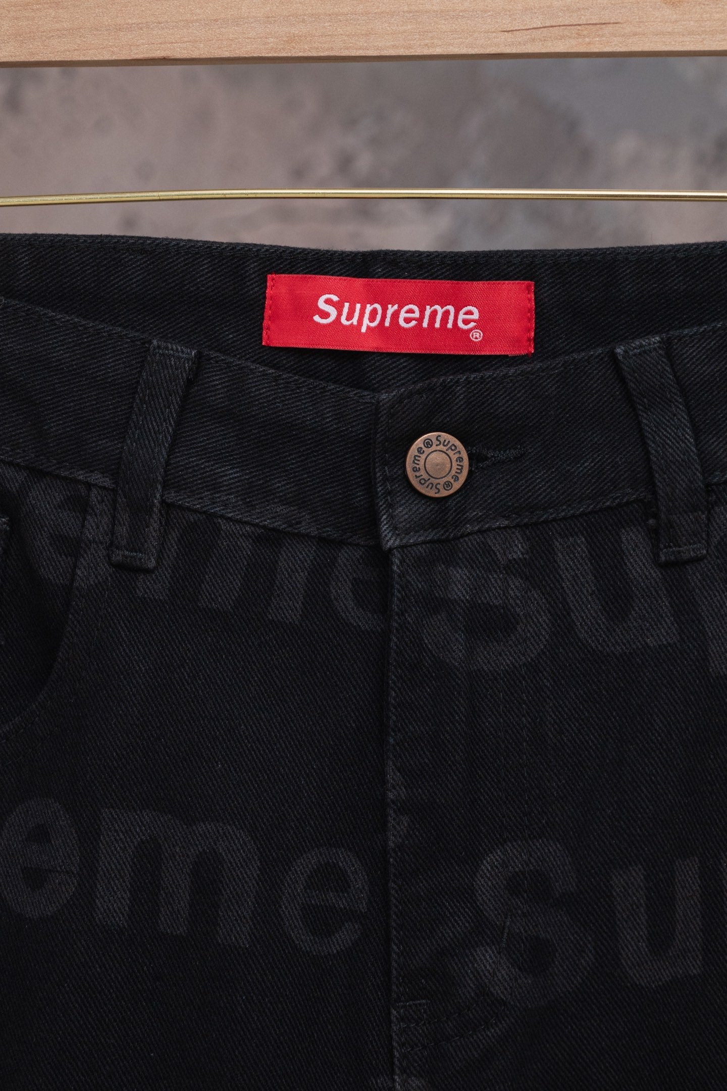 Black denim pants waistband close-up with red Supreme label