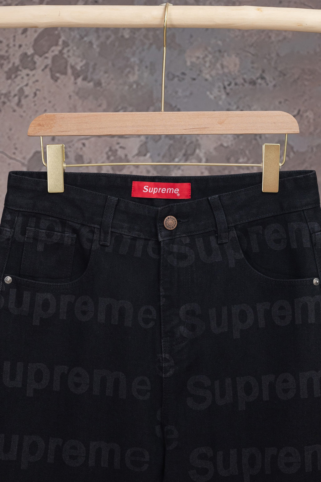 Black denim pants waist close-up with red Supreme label and button