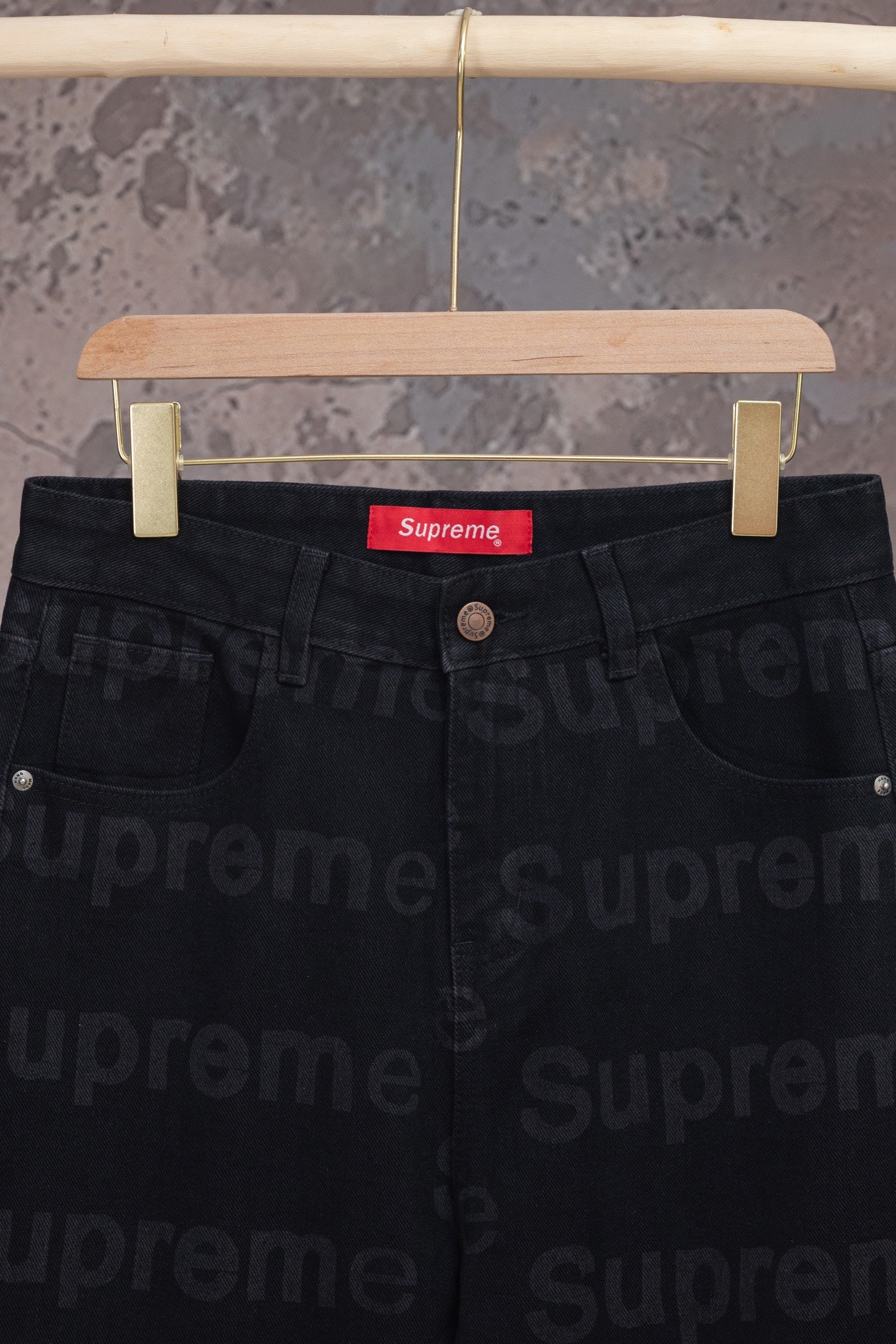 Black denim pants waist close-up with red Supreme label and button