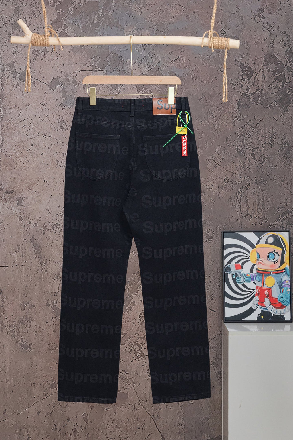 Black denim pants with Supreme red waistband label and hanging tag