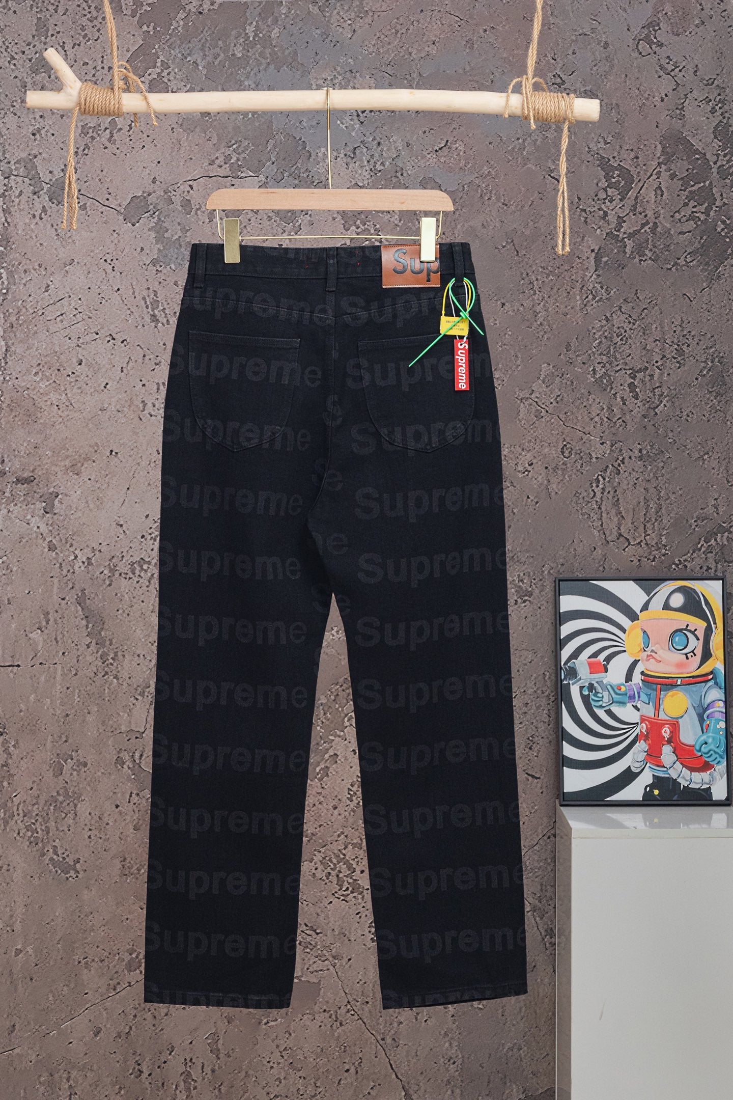 Black denim pants with Supreme red waistband label and hanging tag