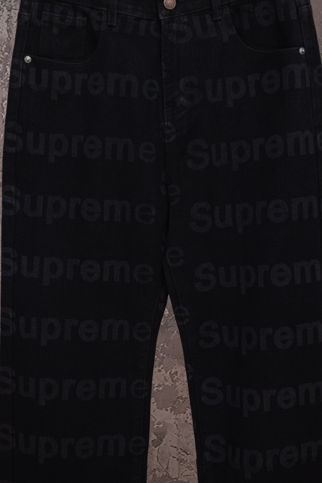 Black denim pants full leg view hanging on a hanger