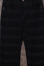 Black denim pants full leg view hanging on a hanger