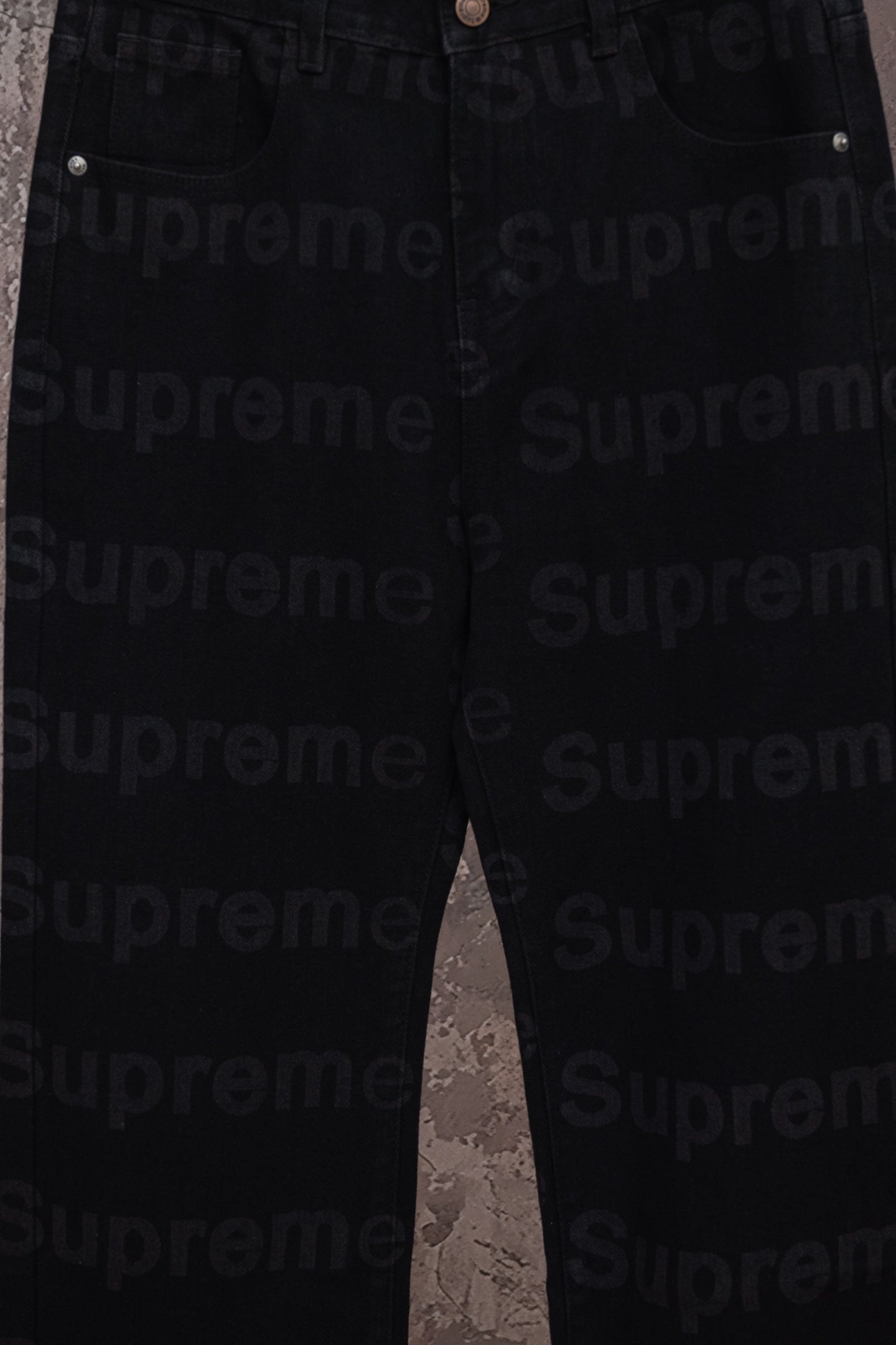 Black denim pants full leg view hanging on a hanger