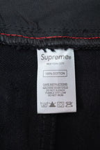 Black denim pants care label showing Supreme and 100% cotton