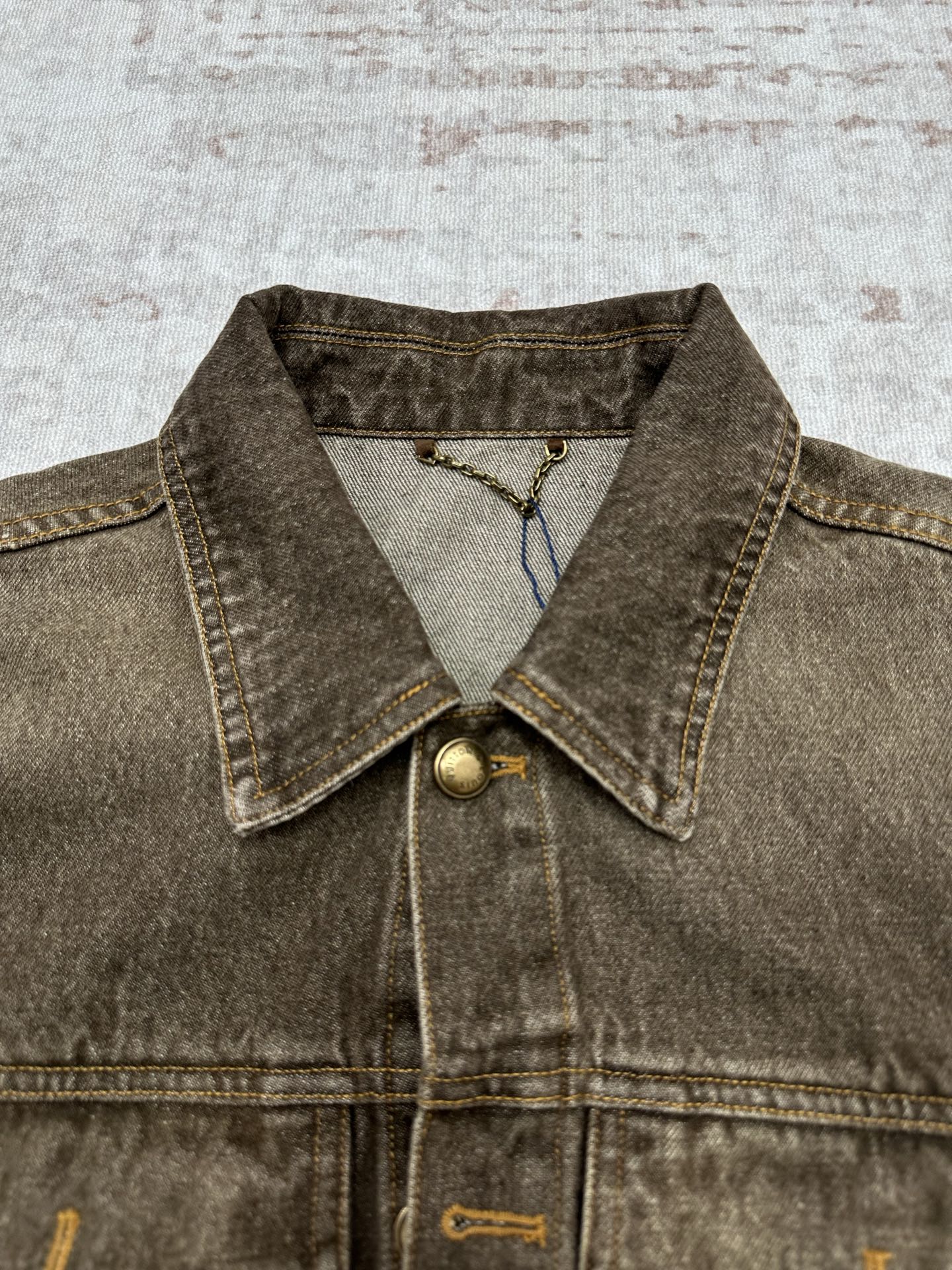 Dark gray denim jacket close-up of pointed collar with brass snap and inner print