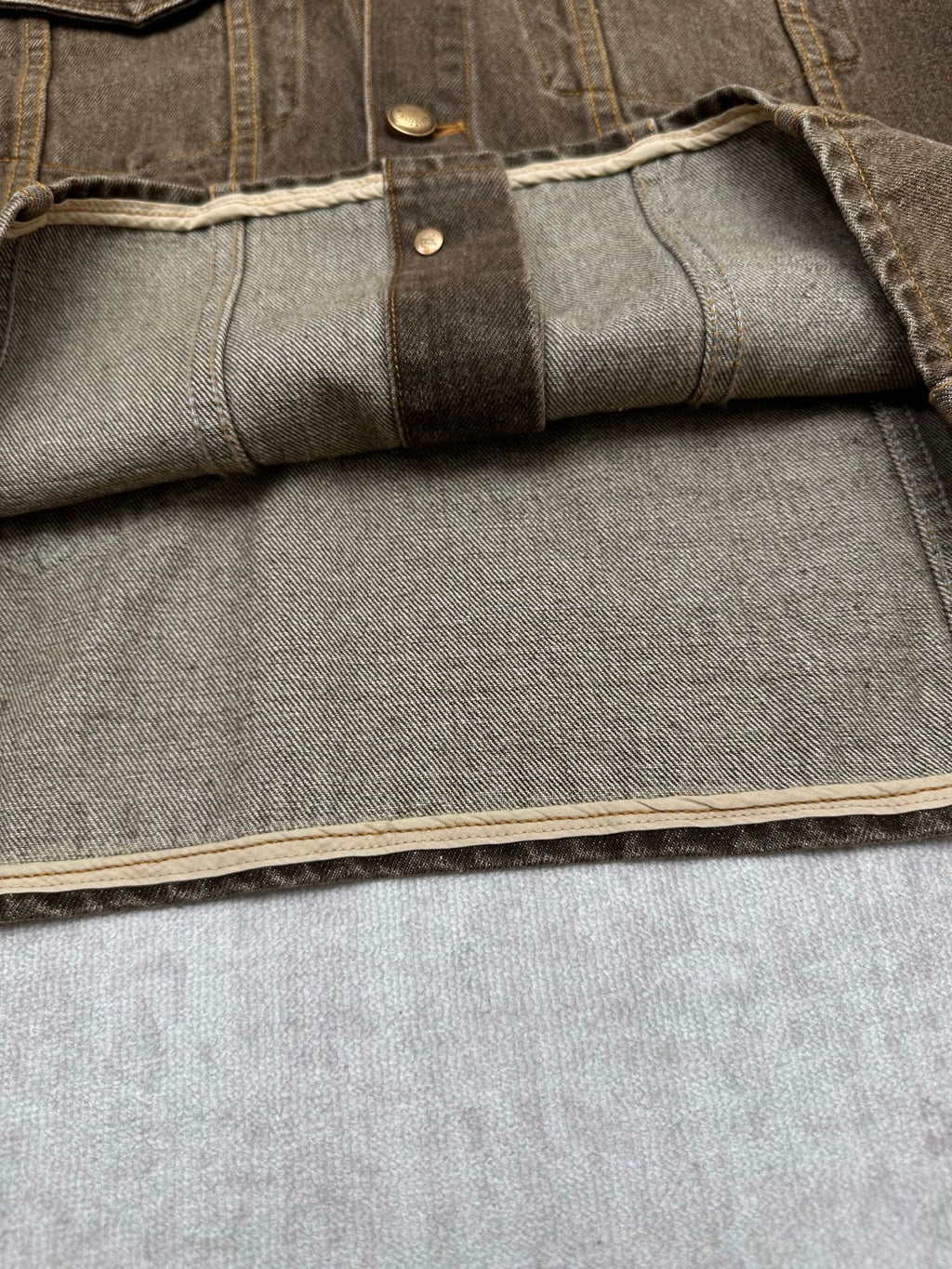 Dark gray denim jacket sleeve cuff with interior panel and topstitched edge