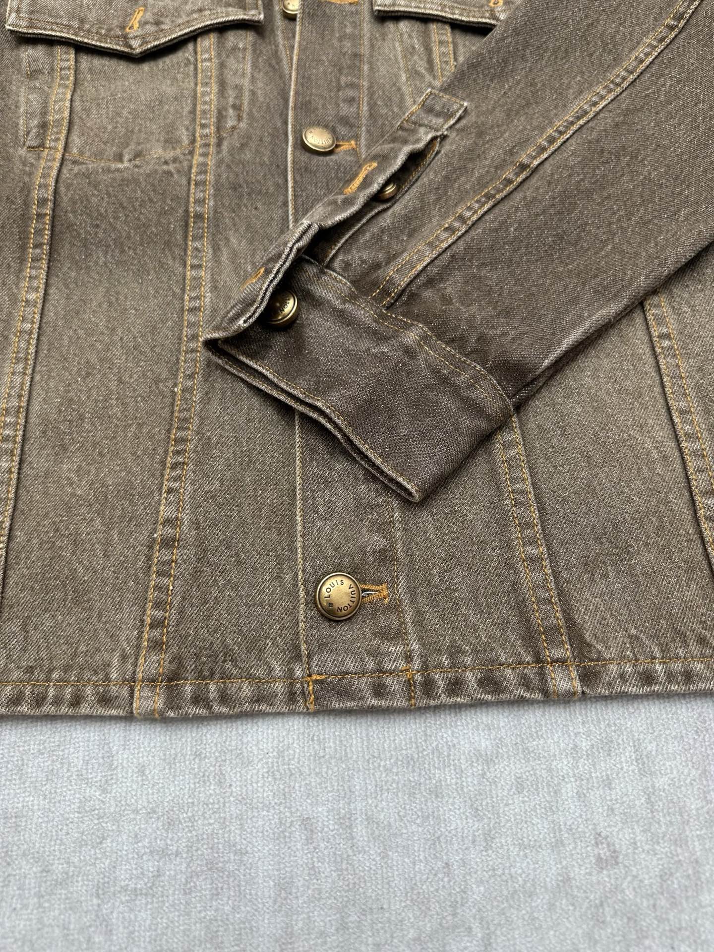 Dark gray denim jacket pocket and button details with visible stitched seams