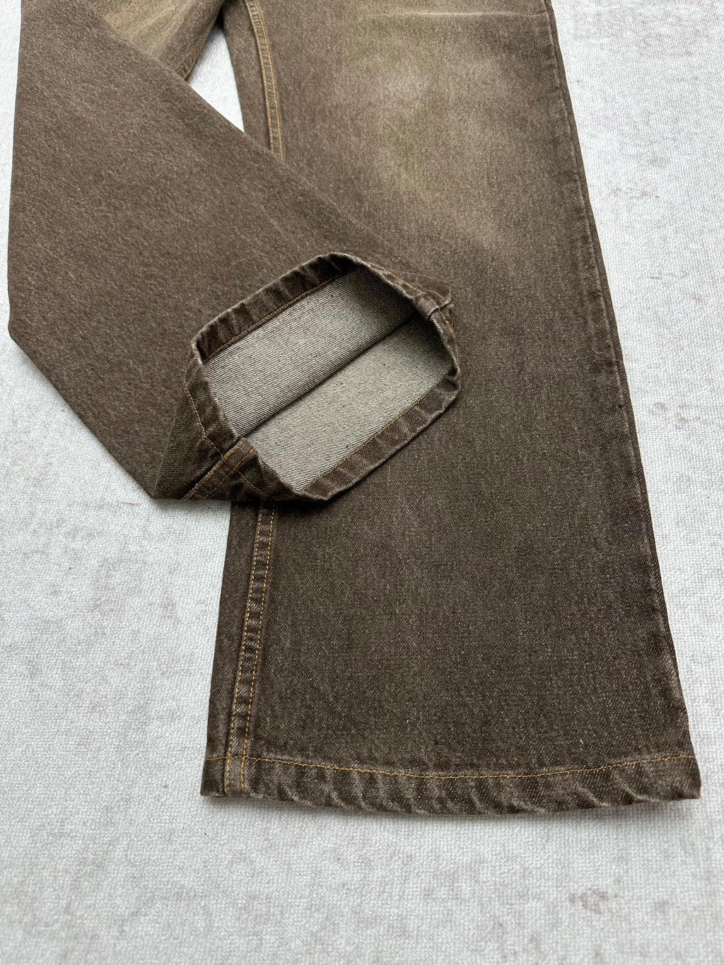 Brown denim jeans folded view showing inner pocket and waistband stitching