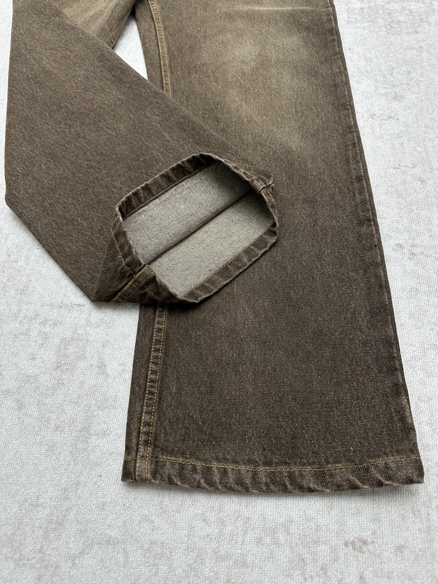 Brown denim jeans folded view showing inner pocket and waistband stitching