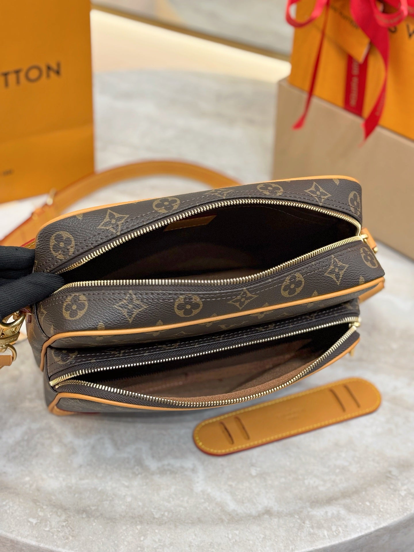 Louis Vuitton bag open view with dark interior lining, double zippers, and tan trim