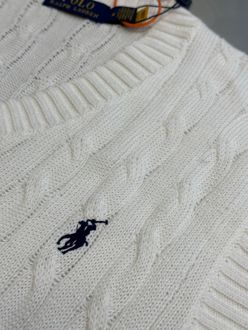 White cable-knit sweater vest with small black polo horse logo on chest