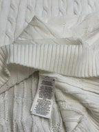 White cable-knit sweater vest with care label near the collar and V-neck