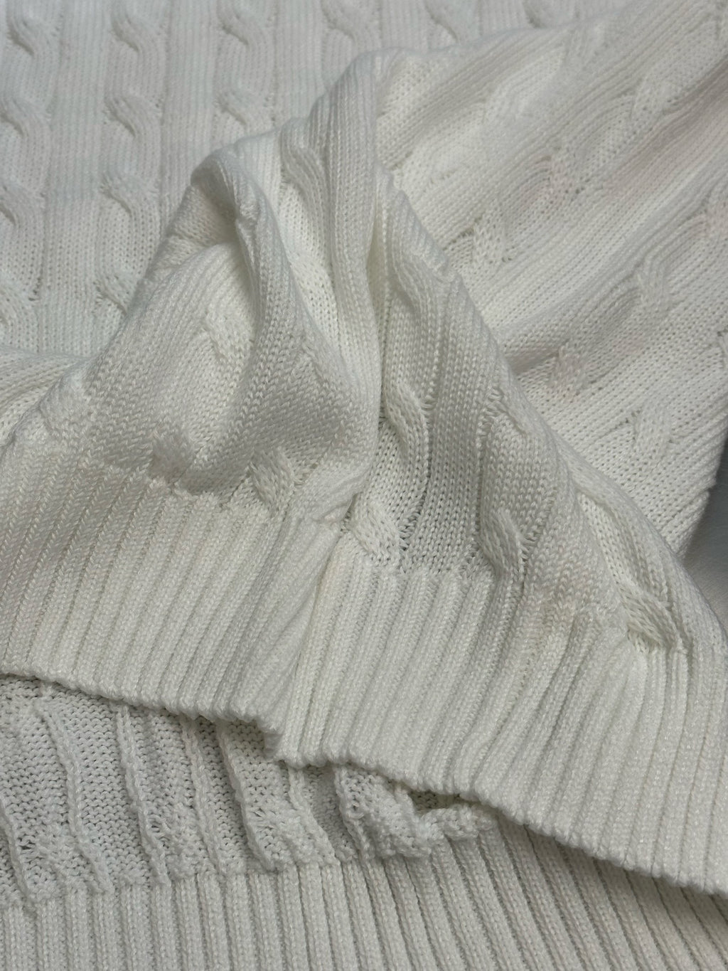 White cable-knit sweater vest close-up of ribbed cuff and hem