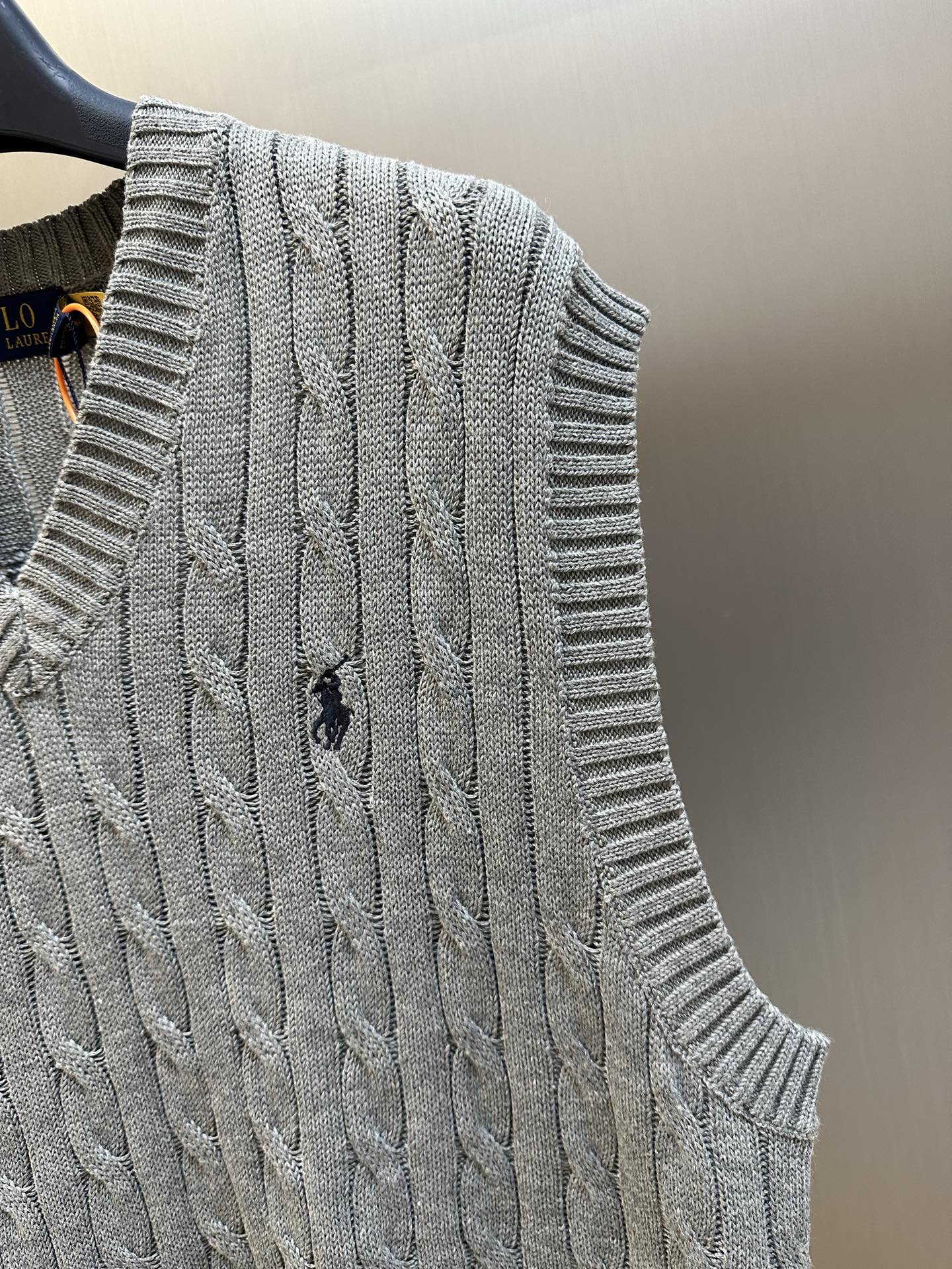 Gray cable-knit sleeveless sweater vest close-up with textured knit pattern