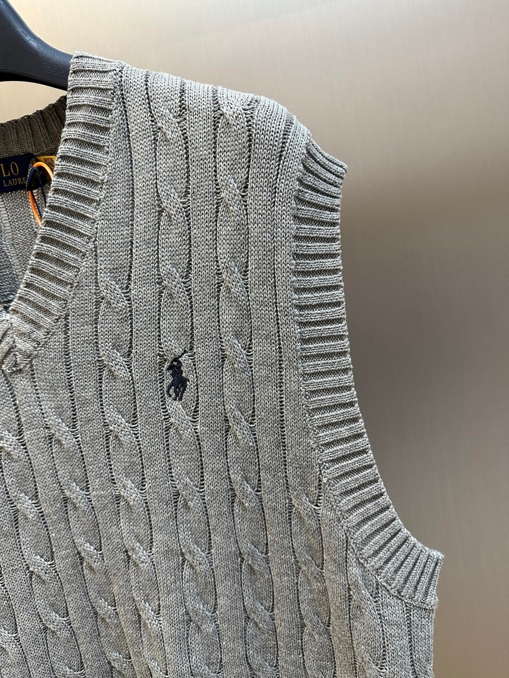 Gray cable-knit sweater vest with ribbed armhole and textured cable pattern