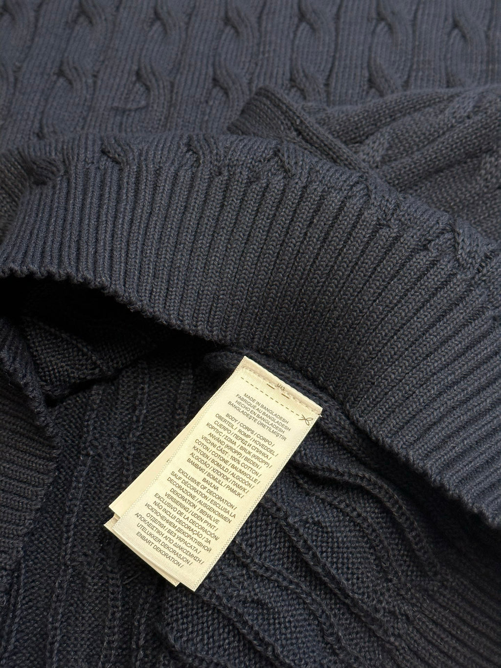 Navy knit sweater vest with woven size tag near the hem