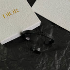 Black open cuff bracelet with embossed Dior logo detail, side view