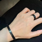 Black engraved cuff bracelet worn on hand, open adjustable band