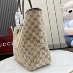 Beige GG monogram tote bag viewed from side/back with dark brown trim and top handle.