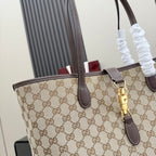 Close-up of beige GG monogram tote bag with dark brown leather trim and gold clasp.