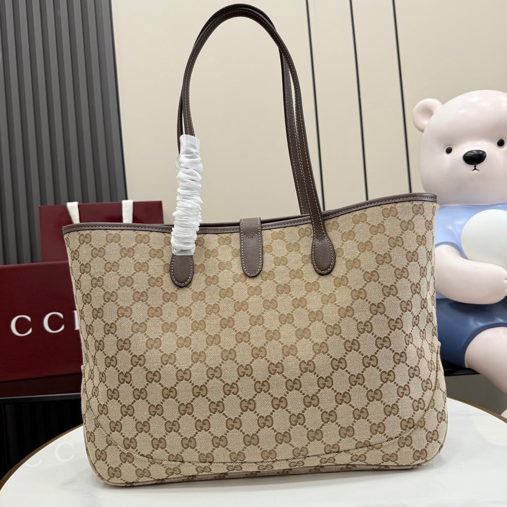 Beige GG monogram tote bag with dark brown leather handles and gold central clasp.